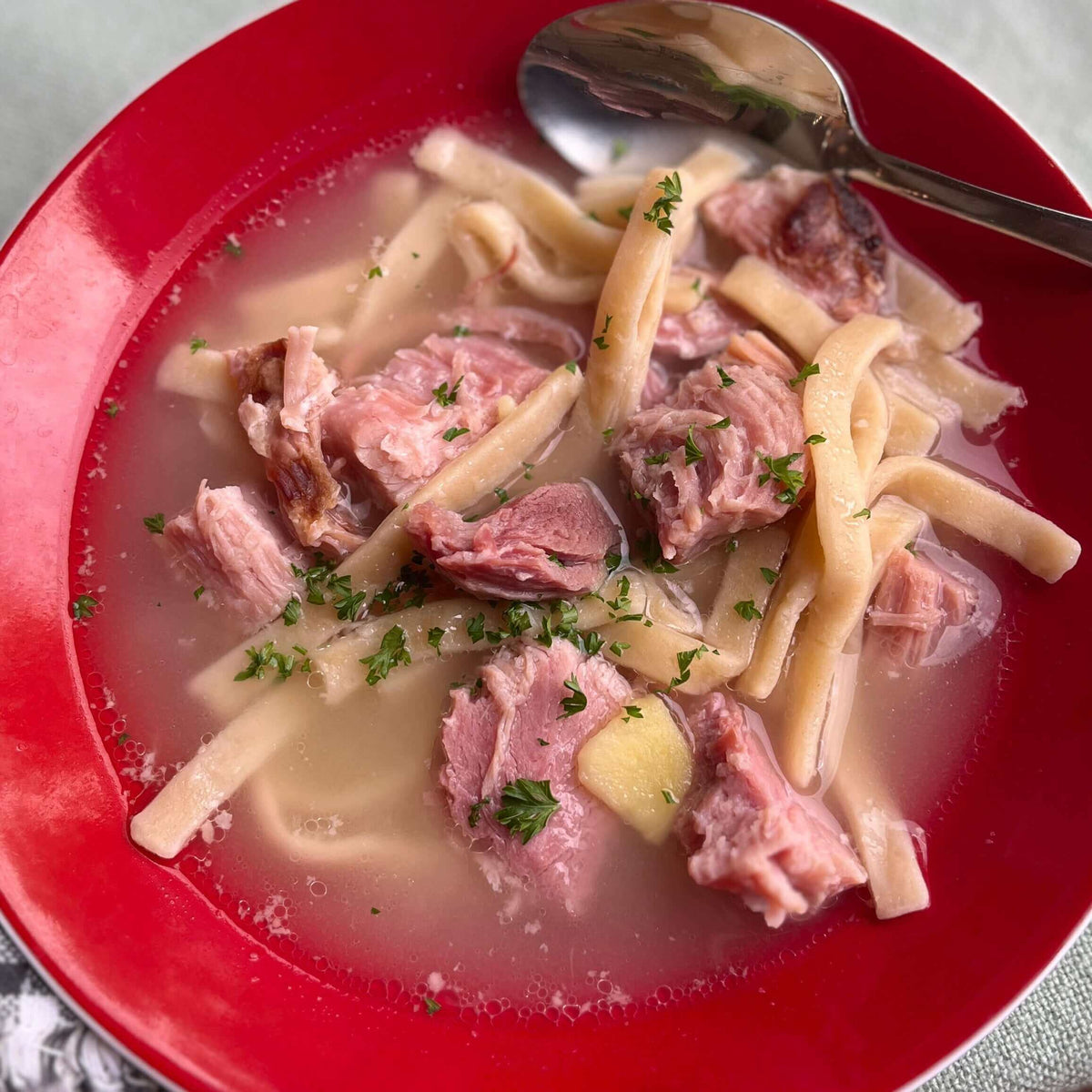 Ham and tender egg noodles with broth.
