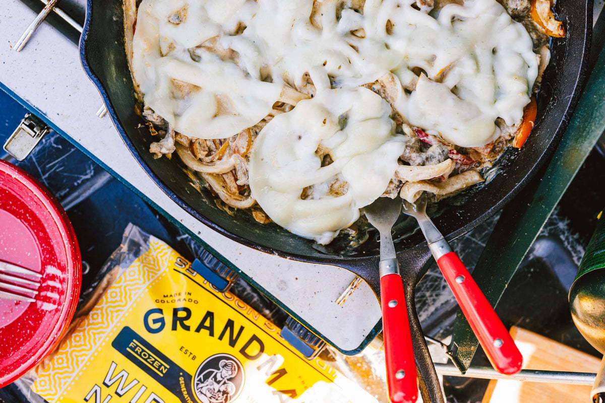 Cast iron skillet with philly cheesesteak and melted cheese ready to be served. 