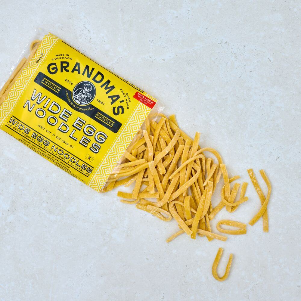 Package of Grandma's Frozen Egg Noodles with noodles spilling onto kitchen counter.