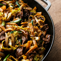 Cabbage stir fry with wide egg noodles in cast iron pan. 